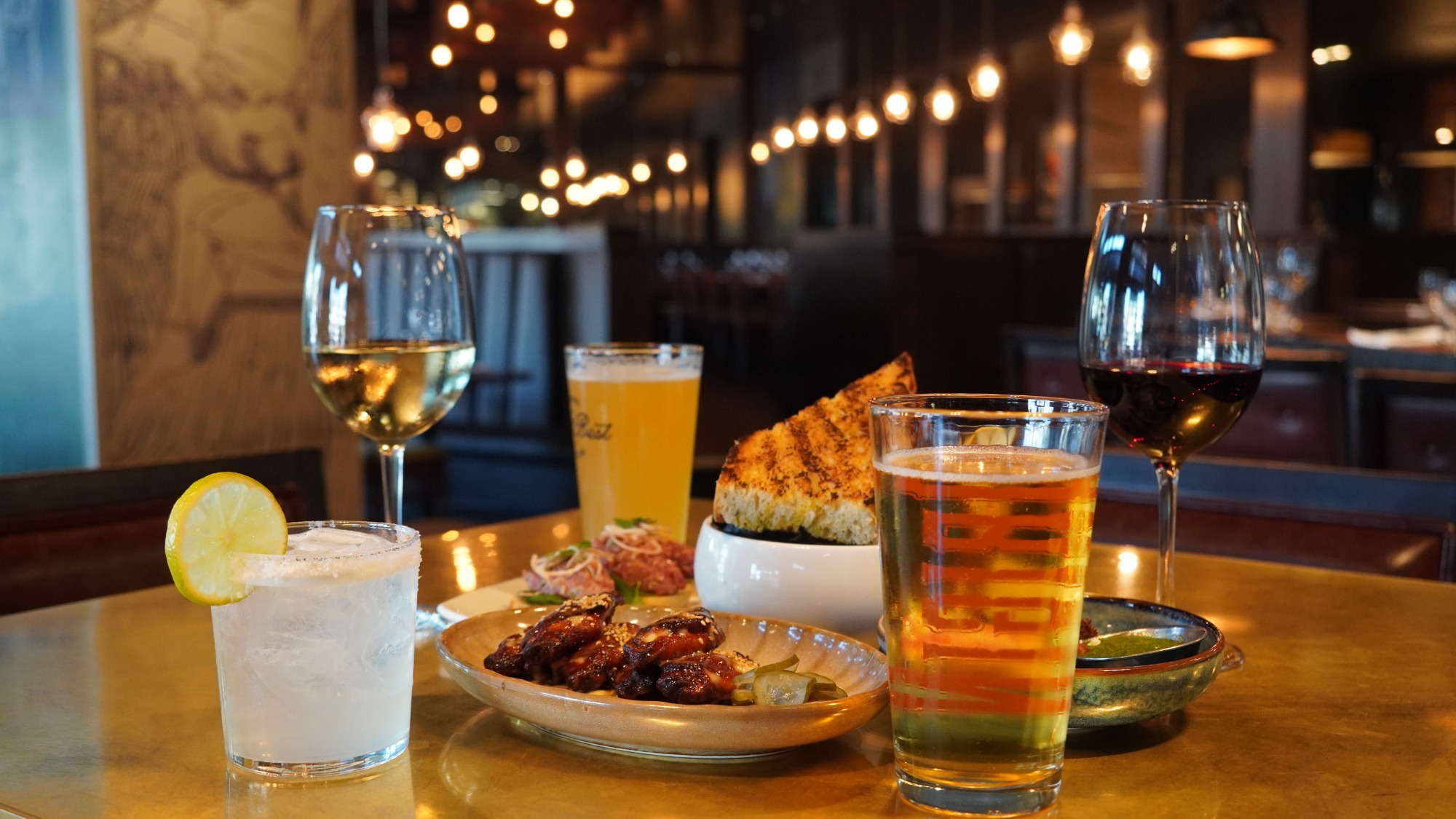 Ember Hour spread at notable - The Steakhouse: notable chicken wings, parm fries, wood-fire grilled bread, a margarita, beer and wine on the lounge bar