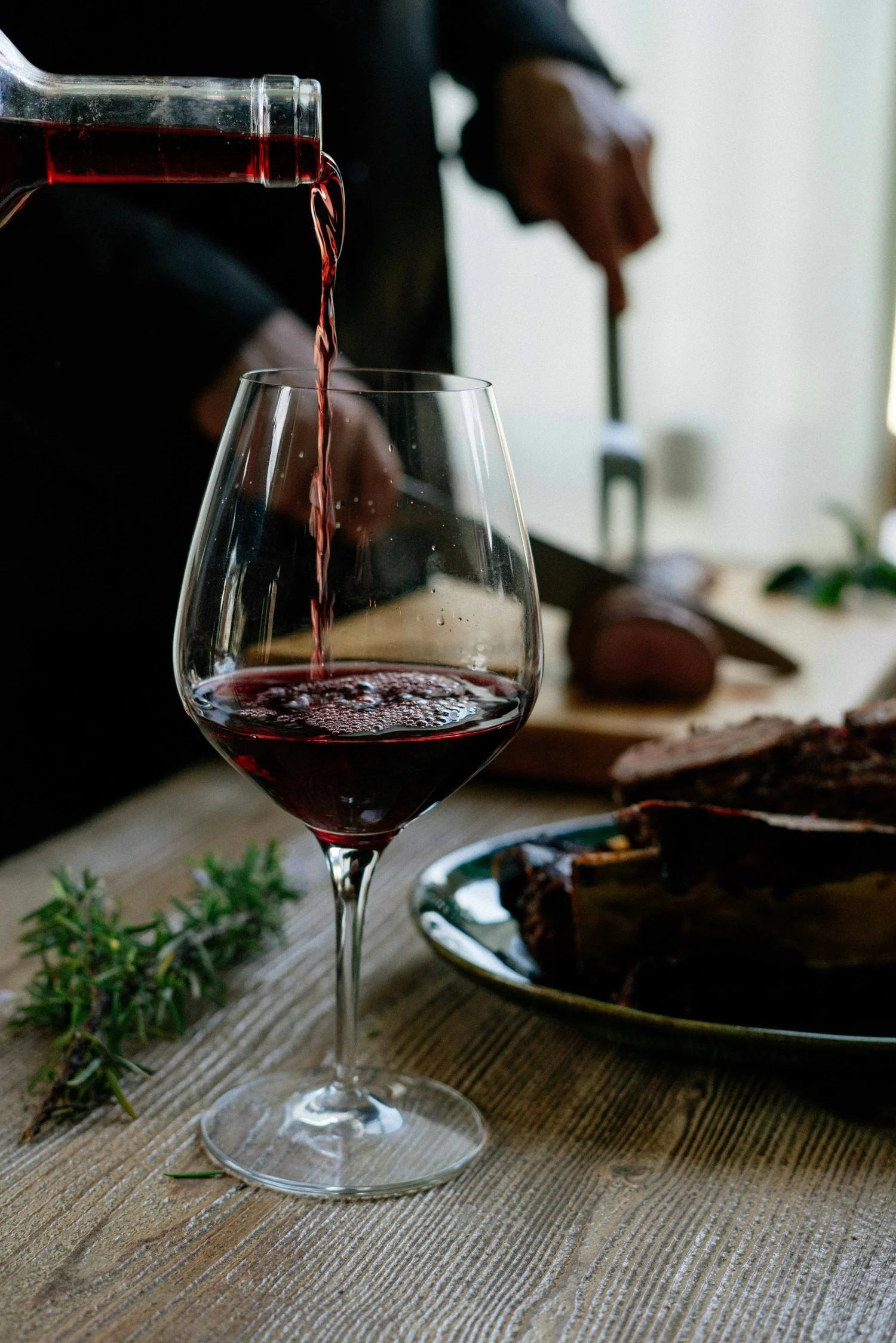 Red wine being poured at the table during Wine Wednesday at notable - The Steakhouse