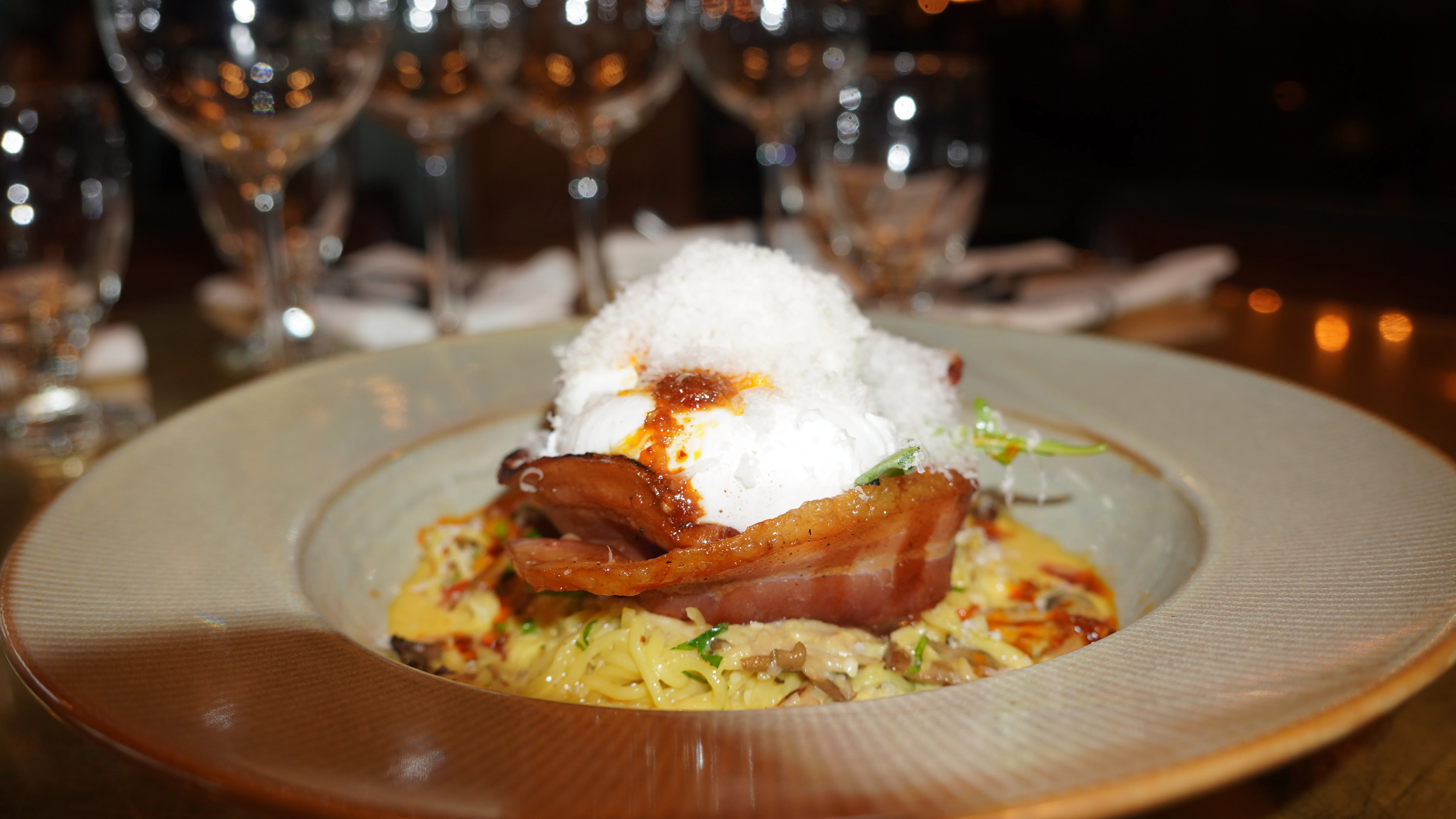 Brunch plate of thick-cut bacon over creamy pasta with a poached egg and chilli oil at our Bowness Road NW steakhouse